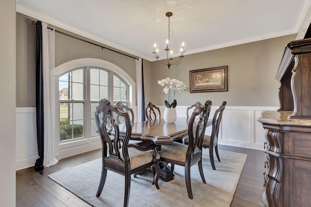 dining space featuring wainscoting, crown molding, an inviting chandelier, and wood finished floors