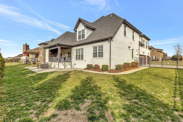 rear view of property featuring a yard, fence, a patio, and brick siding