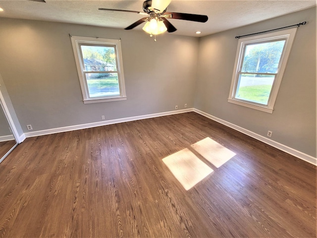 unfurnished room featuring a ceiling fan, a textured ceiling, baseboards, and dark wood-type flooring