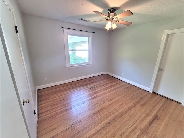 unfurnished bedroom with visible vents, a textured ceiling, baseboards, and wood finished floors