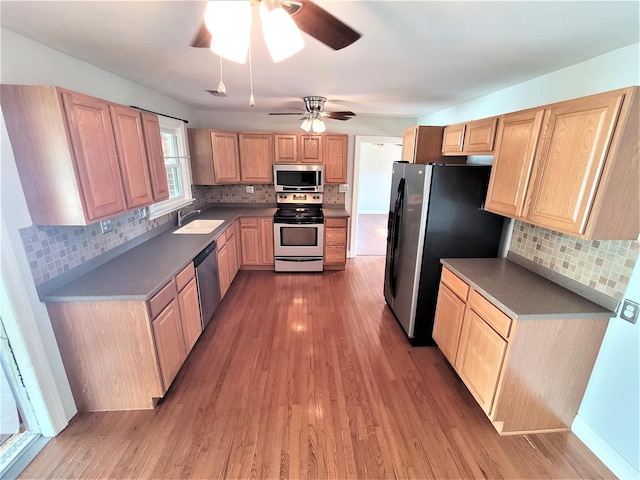 kitchen with light wood-style flooring, decorative backsplash, stainless steel appliances, and a sink