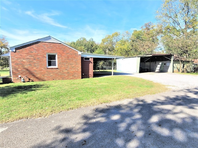 view of side of property with driveway, a yard, an attached carport, and brick siding