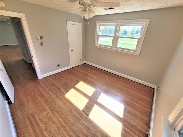 unfurnished bedroom with a textured ceiling, wood finished floors, visible vents, and baseboards