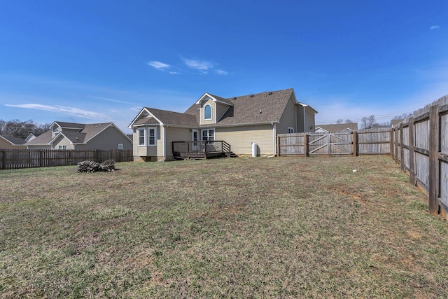 rear view of house with a gate, a fenced backyard, a yard, and a wooden deck