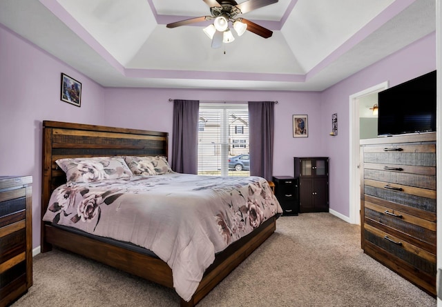 carpeted bedroom featuring ceiling fan, a raised ceiling, and baseboards