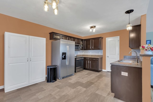 kitchen with dark brown cabinetry, a sink, appliances with stainless steel finishes, tasteful backsplash, and decorative light fixtures