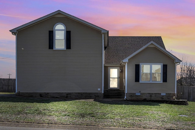 traditional home with a shingled roof, entry steps, crawl space, a front yard, and fence