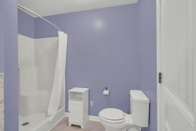 full bathroom with a shower stall, toilet, and baseboards