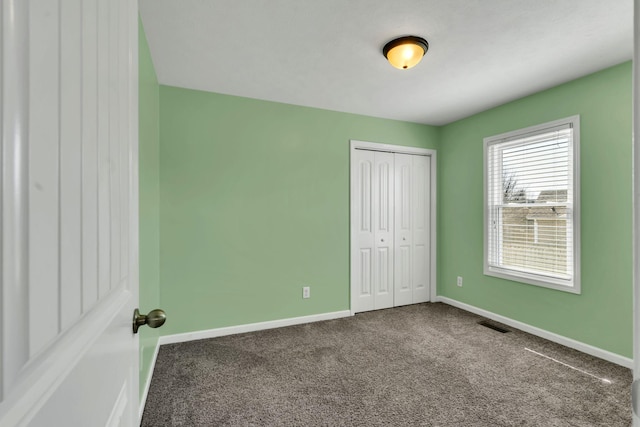 unfurnished bedroom with a closet, carpet flooring, visible vents, and baseboards