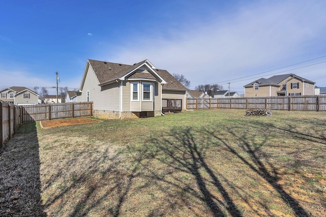 rear view of house with crawl space, a fenced backyard, and a lawn