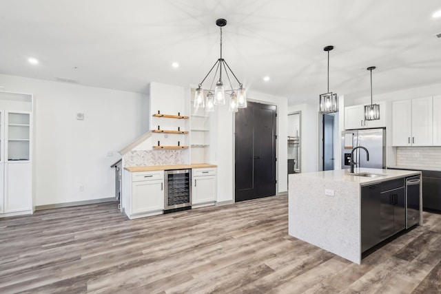 kitchen featuring stainless steel refrigerator with ice dispenser, open shelves, light wood-style floors, a sink, and beverage cooler