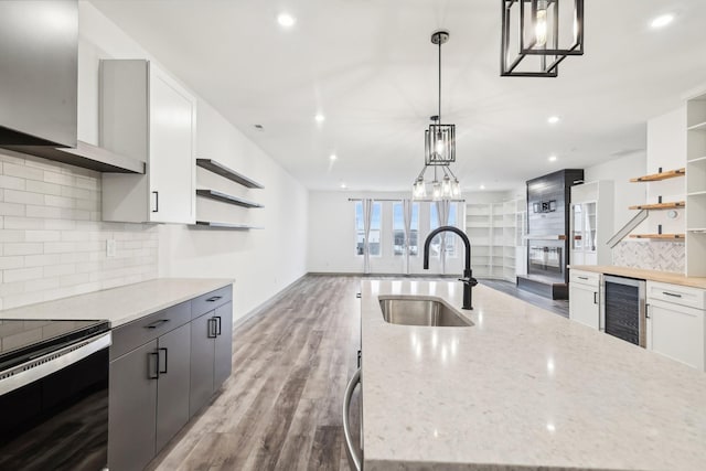 kitchen with beverage cooler, wood finished floors, a sink, stainless steel electric range, and open shelves