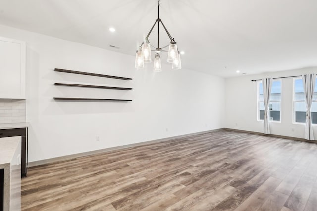 unfurnished living room featuring baseboards, visible vents, wood finished floors, and recessed lighting