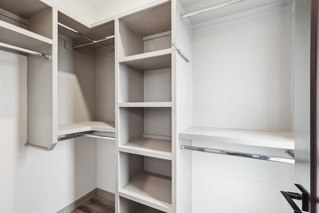 walk in closet with dark wood-style floors