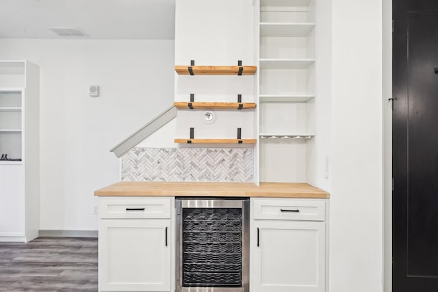 bar with wine cooler, wood finished floors, visible vents, backsplash, and a dry bar