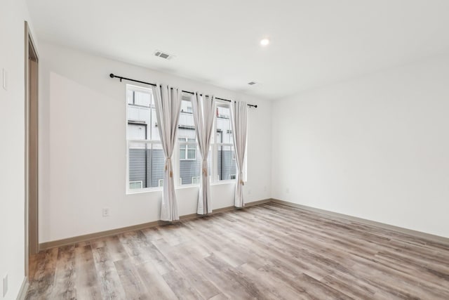 empty room with visible vents, baseboards, wood finished floors, and recessed lighting