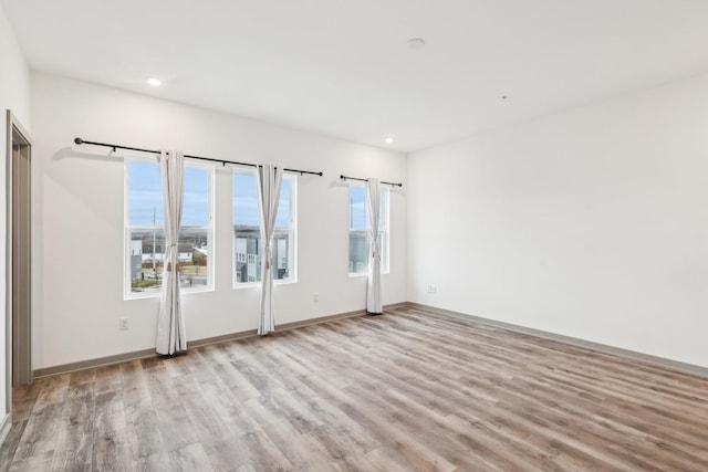 empty room featuring baseboards, recessed lighting, and light wood-style floors