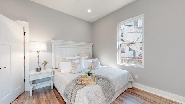 bedroom with multiple windows, baseboards, wood finished floors, and recessed lighting