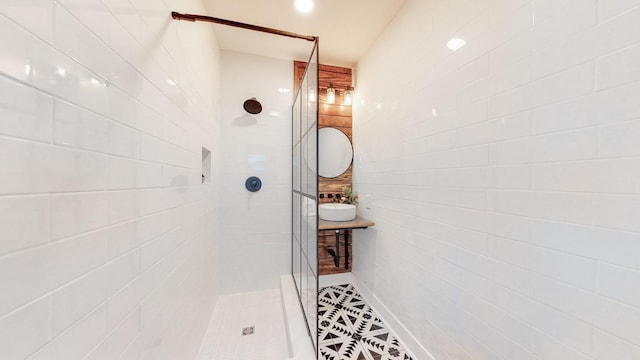 bathroom featuring a sink, tile patterned flooring, and a tile shower