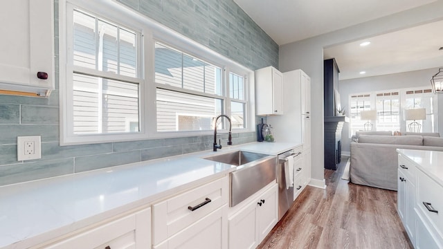 kitchen with a sink, white cabinetry, light countertops, and dishwasher