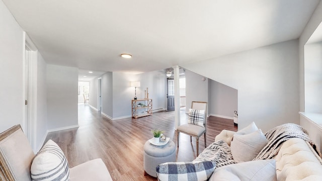 living area with light wood-style flooring, baseboards, and ceiling fan