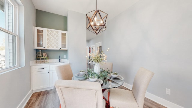 dining space with an inviting chandelier, wood finished floors, and baseboards