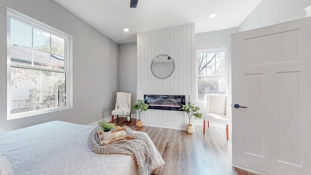 bedroom with ceiling fan, recessed lighting, wood finished floors, baseboards, and a glass covered fireplace