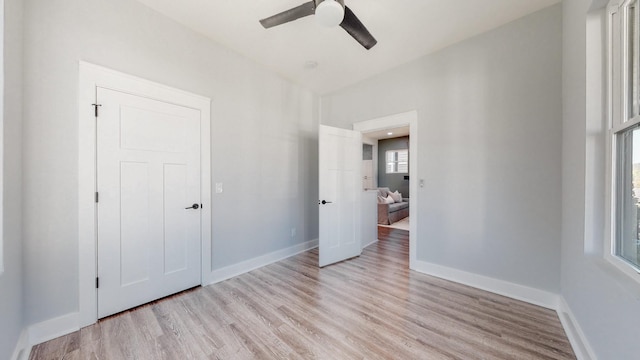 unfurnished bedroom featuring light wood-style flooring, baseboards, and a ceiling fan