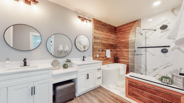 full bathroom with wooden walls, a sink, a freestanding bath, a marble finish shower, and double vanity