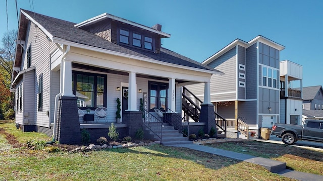 view of front of house featuring a front yard, covered porch, roof with shingles, and a chimney