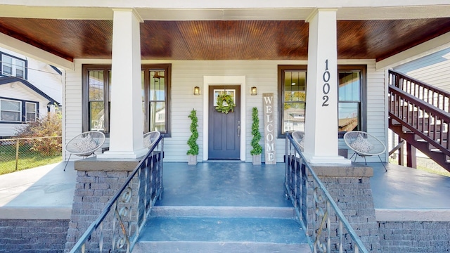 doorway to property featuring covered porch and fence