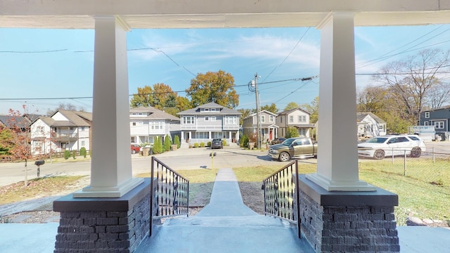 view of patio with a residential view, fence, and a porch