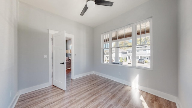 empty room with ceiling fan, light wood-style flooring, and baseboards