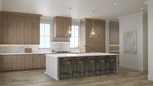 kitchen with light wood-style floors, backsplash, a center island with sink, and a kitchen breakfast bar