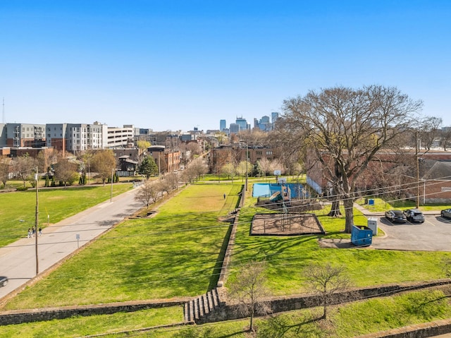 view of home's community with playground community, a view of city, and a lawn