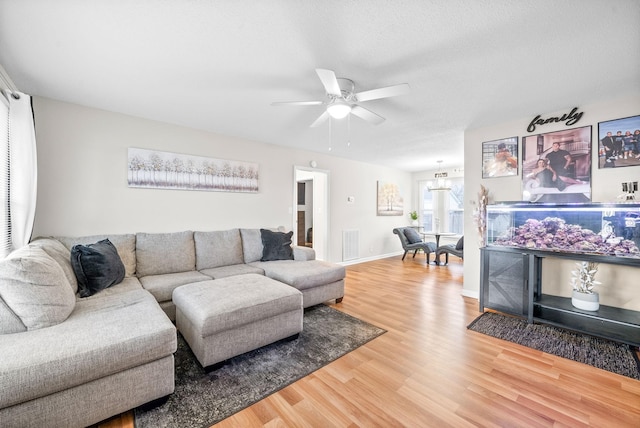 living area featuring baseboards, visible vents, a ceiling fan, wood finished floors, and a textured ceiling