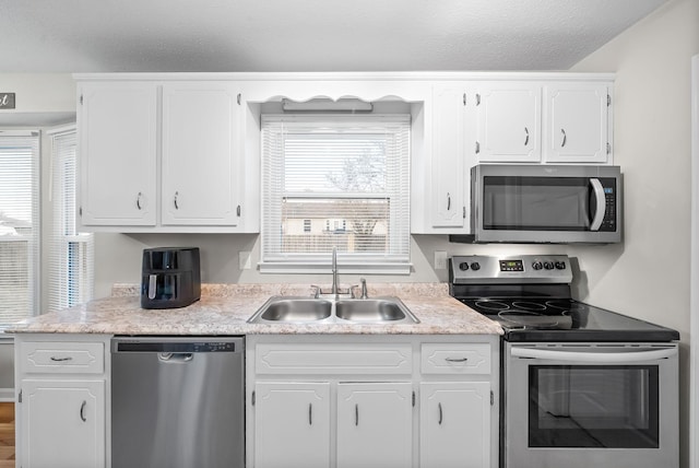 kitchen featuring stainless steel appliances, light countertops, white cabinets, a sink, and a textured ceiling