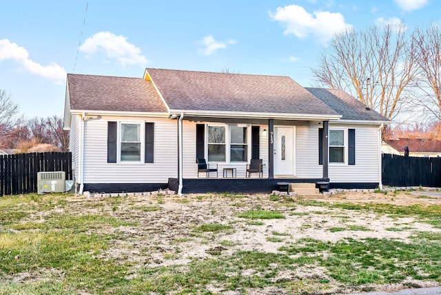 ranch-style home featuring a shingled roof, cooling unit, covered porch, and fence