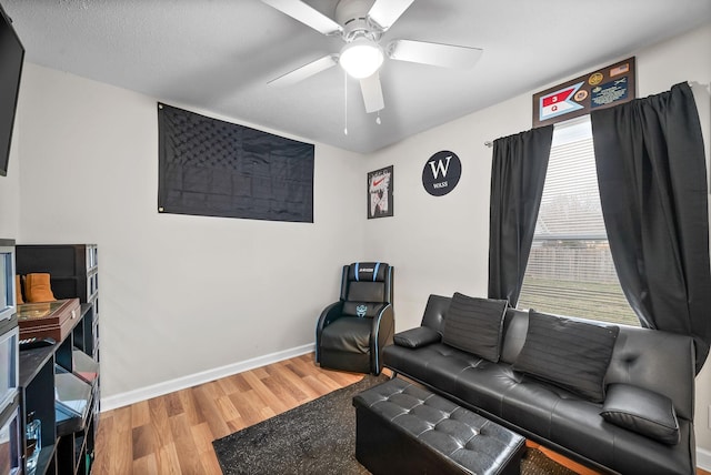 living room featuring ceiling fan, wood finished floors, and baseboards