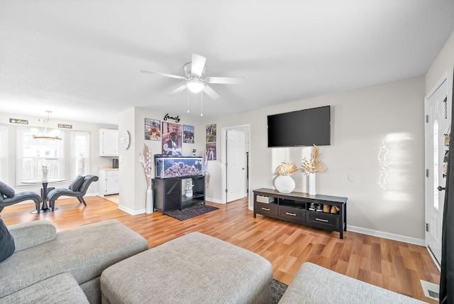 living area with light wood-style floors, baseboards, and a ceiling fan