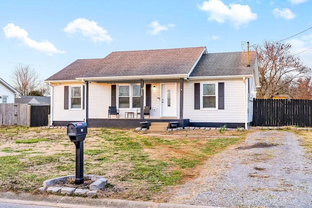 view of front of home with driveway, a porch, roof with shingles, and fence