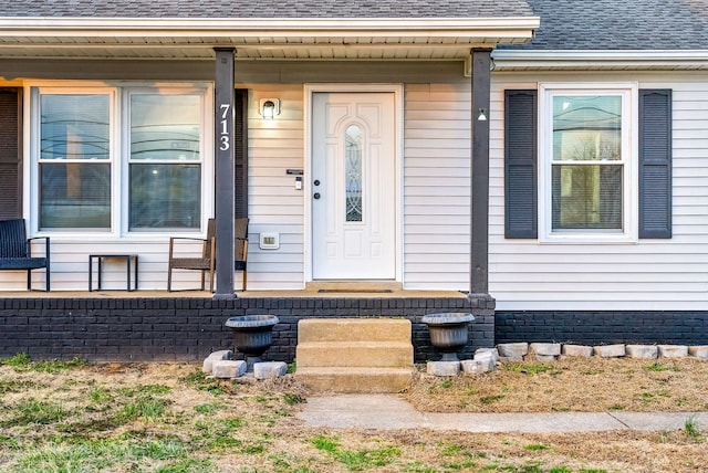 property entrance with a shingled roof and covered porch