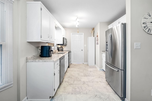 kitchen featuring marble finish floor, stainless steel appliances, light countertops, white cabinetry, and a sink