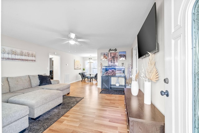 living room with baseboards, a ceiling fan, visible vents, and light wood-style floors