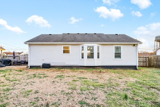 back of property with a shingled roof, a patio area, fence, and a lawn