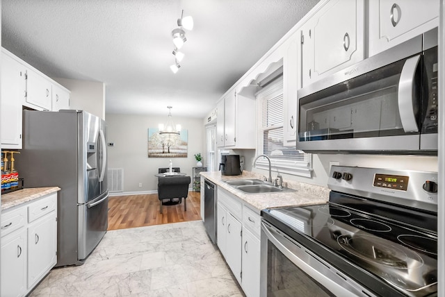 kitchen with marble finish floor, stainless steel appliances, light countertops, white cabinets, and a sink