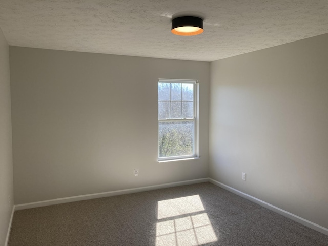 empty room featuring carpet floors, a textured ceiling, and baseboards