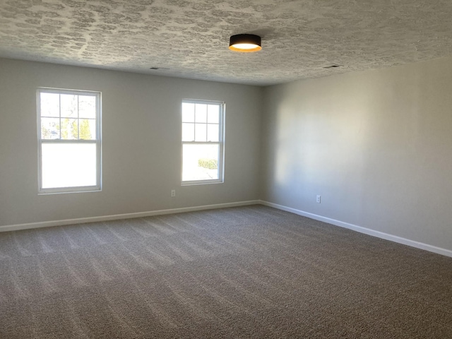 unfurnished room with dark colored carpet, a textured ceiling, and baseboards