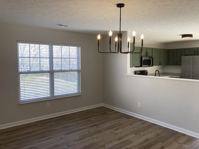 unfurnished dining area with a textured ceiling, dark wood-style flooring, a notable chandelier, and baseboards