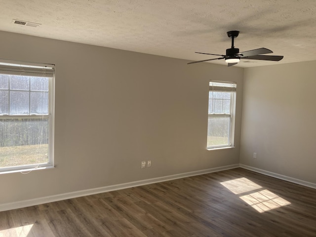 unfurnished room with dark wood-type flooring, visible vents, a textured ceiling, and baseboards